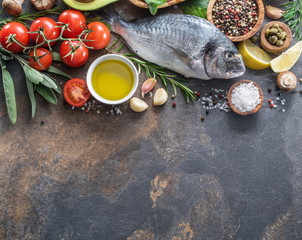 Raw dorado fish with spices and vegetables on the graphite board.