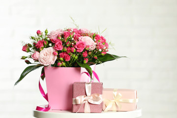 Beautiful bouquet of flowers and gift boxes on table against light background. Space for text