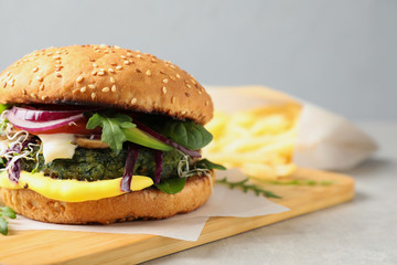 Board with tasty vegetarian burger on table. Space for text