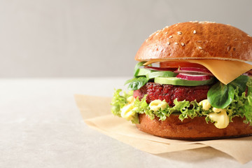 Tasty vegetarian burger with beet cutlet on table against light background. Space for text
