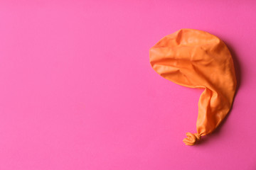 Orange deflated balloon on color background, top view with space for text