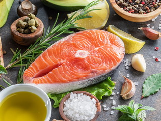 Raw salmon with spices and vegetables on the graphite board.