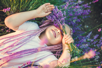 Caucasian girl lies in the grass and closes her eyes with a bouquet of lavender