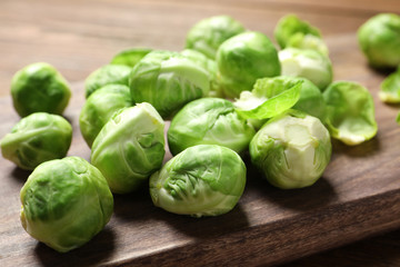 Wooden board with Brussels sprouts on table, closeup