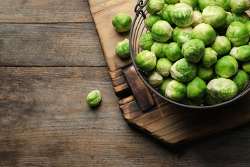 Metal basket with fresh Brussels sprouts on wooden background, top view. Space for text