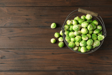 Metal basket with fresh Brussels sprouts on wooden background, top view. Space for text