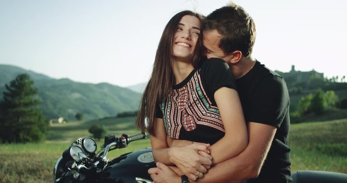 Pretty young couple happy spending a lovely time together in the middle of nature sitting on their motorcycle