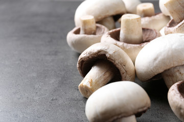 Fresh champignon mushrooms on grey background, closeup. Space for text