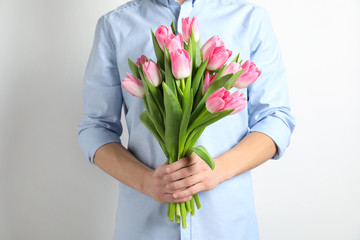 Man holding bouquet of beautiful spring tulips on light background, closeup. International Women's Day