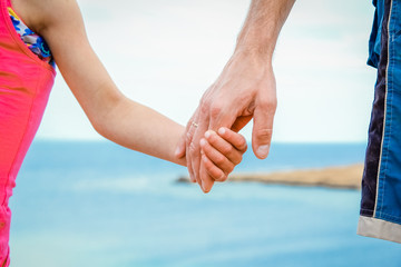 Beautiful hands of parent and child on sea background