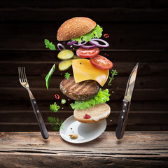 Hamburger ingredients falling down one by one to create a perfect meal. Colorful conceptual picture of burger cooking.