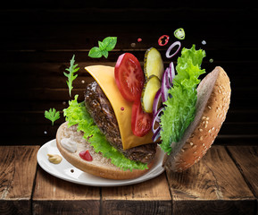 Hamburger ingredients falling down one by one to create a perfect meal. Colorful conceptual picture of burger cooking.