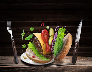 Hamburger ingredients falling down one by one to create a perfect meal. Colorful conceptual picture of burger cooking.