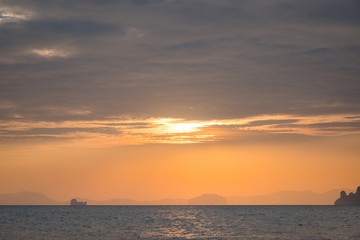 Naklejka na ściany i meble Sunset on the sea with a coastal strip on the horizon