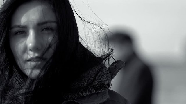 Sad woman looking camera with wind blowing her long hair slow motion