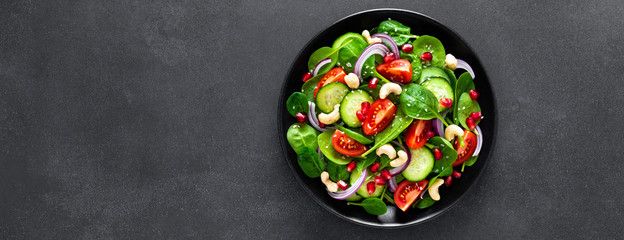 Spinach salad with fresh cucumbers, tomato, onion, pomegranate, sesame seeds and cashew nuts on...