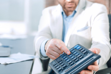 Businessman pointing to calculator in hand.