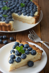 Healthy dessert. Piece of blueberry tart or cake with cream. Fresh sweet dessert with fruits. Top view. Wooden, rustic background.