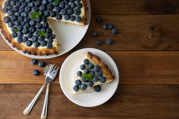 Blueberry Tart. Homemade piece of berry tart, cake with cream. Fresh sweet dessert with fruit. Top view. wooden, rustic background.