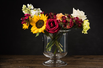 Bouquet of white yellow and red flowers in a vase on a dark background