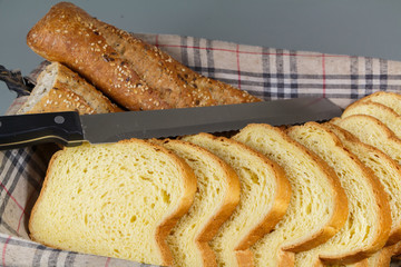 Baguette bread, brioche and knife in a breadbasket