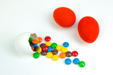 Happy Easter. Broken Easter egg with multi-colored candy decorations. on white background. Copy space for text