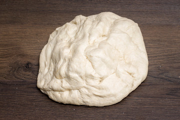 Dough for baking bread on a dark wooden background_