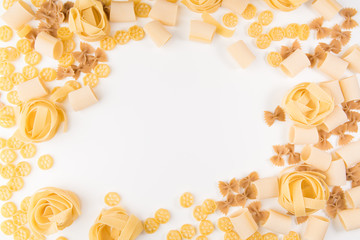 An overhead photo of different types of pasta, including spaghetti, penne, fusilli, and others, flay lay on a white background with a place for text