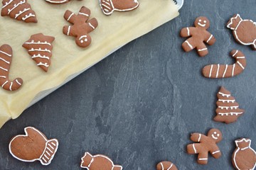 Home-baked gingerbread is decorated with frosting on a kitchen surface with a baking sheet and baking paper - Christmas concept with home-baked cookies in the kitchen