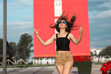 Beautiful young model posing with coffee for the camera on red building background.