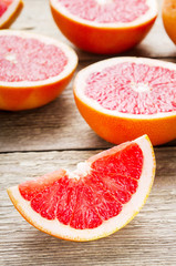 Sliced grapefruit and halves on wooden background. Useful citrus diet fruit