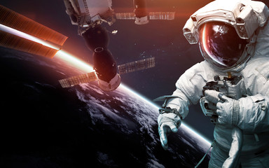 Astronaut at spacewalk against international space station. Science fiction art. Elements of this...