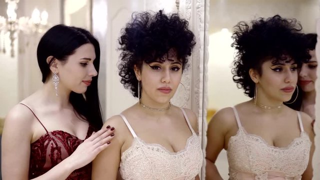 Portrait of two sweet lesbian girls in a sexy lingerie indoor, getting gentle.