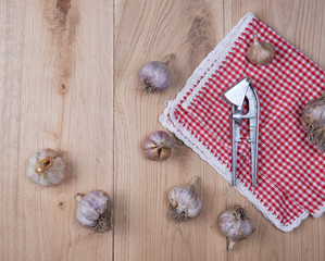 unpeeled fresh garlic fruits and an iron press