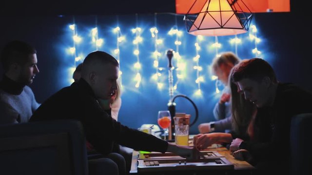 Friends plays backgammon in a blue bar