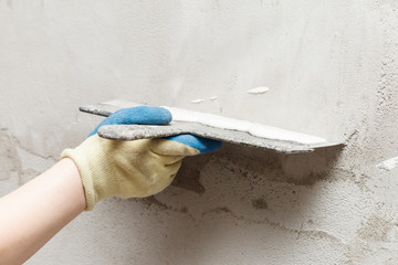 girl in blue gloves. review only a limb. putty putty on the wall. close-up