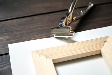 Stretching canvas on wooden stretcher bar and canvas pliers on table