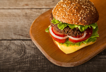 Tasty burger with cheese on wooden table