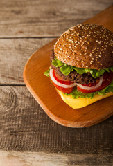 Tasty burger with cheese on wooden table