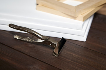 Canvas pliers and white canvas wrapped on stretcher bar on wooden table