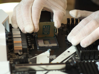 Detail of expert hands in white cloves at processor replacement. Close-up of installation a central processing unit into a socket on computer mainboard.  Working of technical support engineer.