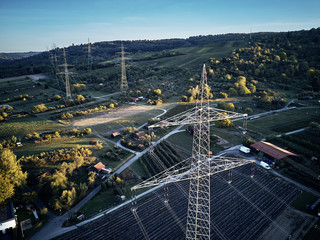 Aerial view of power line pylon near town in the fields on sunset. Orange Teal warm autumn setting