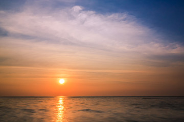 Colorful sunset and sea background with blue, purple and orange tones in abstract idea. It is small orange sun in sky at twilight time and copy space.