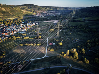 Aerial view of power line pylon near town in the fields on sunset. Orange Teal warm autumn setting