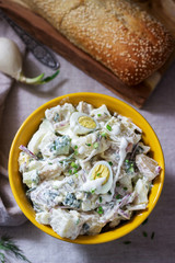 Traditional American potato salad with egg and mayonnaise, served with bread. Rustic style.