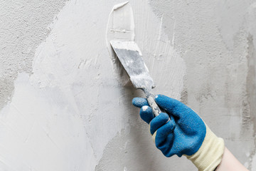 girl in blue gloves. review only a limb. putty putty on the wall. close-up