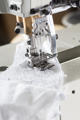 sewing process on sewing professional manufacturing machine with metal needle detailed by white caucasian woman's hands holding lace fabric for lingerie production