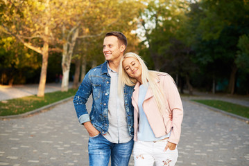 Happy young couple in love hugging and laughing outdoors. Walking in the sunny park