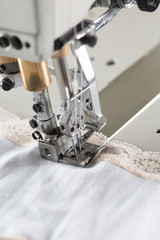 sewing process on sewing professional manufacturing machine with metal needle detailed by white caucasian woman's hands holding lace fabric for lingerie production