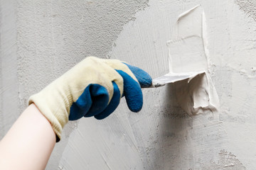 girl in blue gloves. review only a limb. putty putty on the wall. close-up